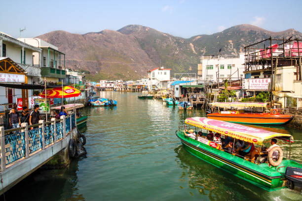 A sightseeing tour boat carrying visitors cruises along Tai O River where traditional houses built on stilts above the tidal flats of Lantau Island are homes to the Tanka people in this old fishing village of Hong Kong.